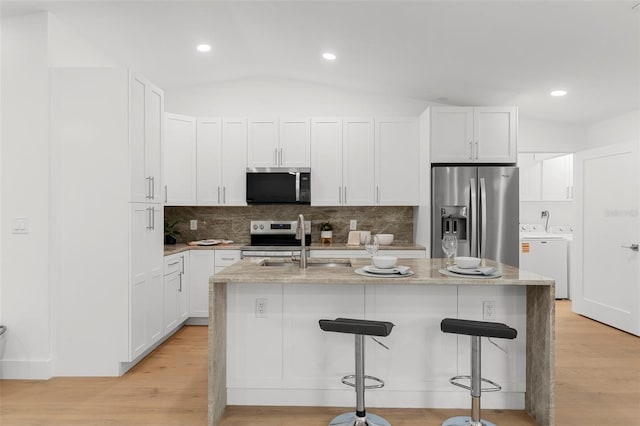 11772 96th Pl, Seminole, FL 33772 - kitchen with washing machine and dryer, appliances with stainless steel finishes, a breakfast bar, light wood-type flooring, and recessed lighting