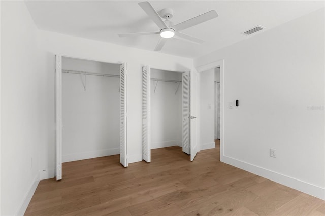 11772 96th Pl, Seminole, FL 33772 - unfurnished bedroom with multiple closets, wood finished floors, and a ceiling fan