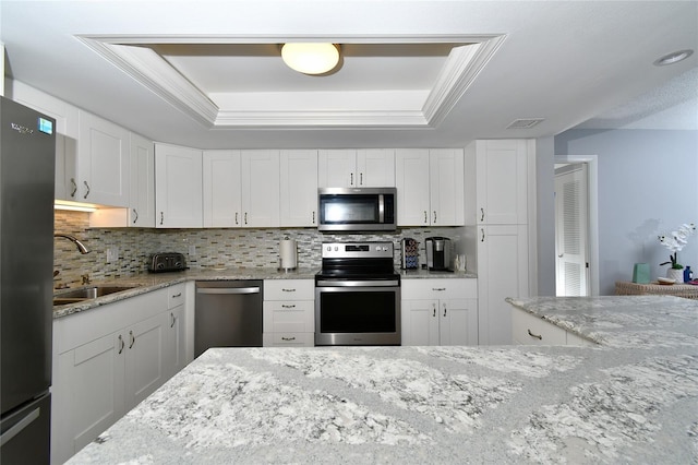 3 Pirates Ln Unit 32A, Punta Gorda, FL 33955 - kitchen featuring appliances with stainless steel finishes, backsplash, a raised ceiling, and white cabinets