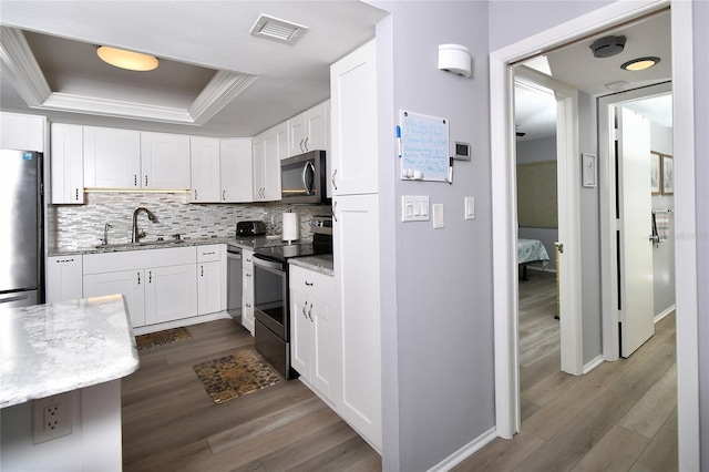 3 Pirates Ln Unit 32A, Punta Gorda, FL 33955 - kitchen featuring a tray ceiling, dark wood-style flooring, stainless steel appliances, white cabinetry, and decorative backsplash