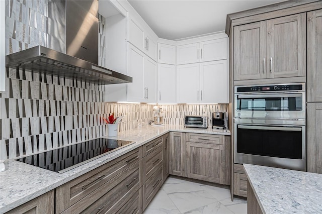 1750 Jamaica Way Unit 131, Punta Gorda, FL 33950 - kitchen with wall chimney range hood, black electric cooktop, stainless steel double oven, light marble finish floors, and decorative backsplash