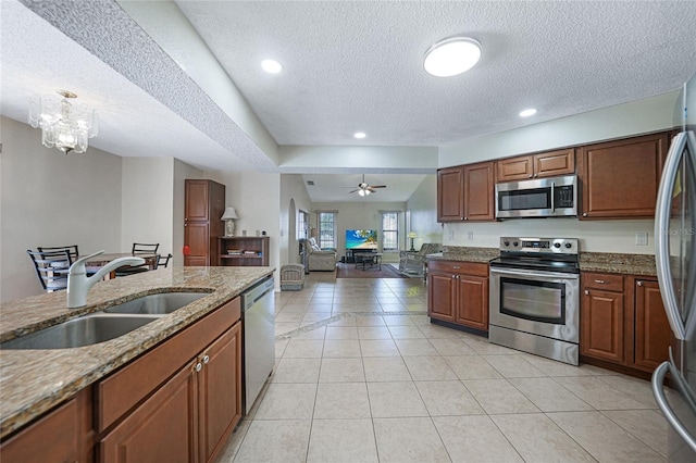 25499 Taltal Dr, Punta Gorda, FL 33983 - kitchen with appliances with stainless steel finishes, a textured ceiling, stone counters, light tile patterned floors, and a ceiling fan