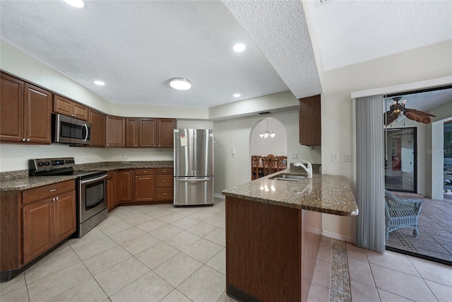 25499 Taltal Dr, Punta Gorda, FL 33983 - kitchen with appliances with stainless steel finishes, a textured ceiling, a peninsula, dark stone counters, and a breakfast bar