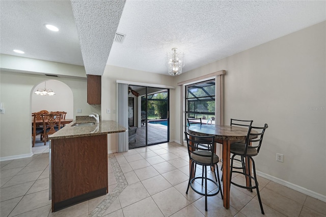 25499 Taltal Dr, Punta Gorda, FL 33983 - dining area with a chandelier, a textured ceiling, light tile patterned floors, arched walkways, and recessed lighting