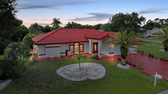 25499 Taltal Dr, Punta Gorda, FL 33983 - rear view of property featuring a tile roof, a yard, stucco siding, an attached garage, and driveway