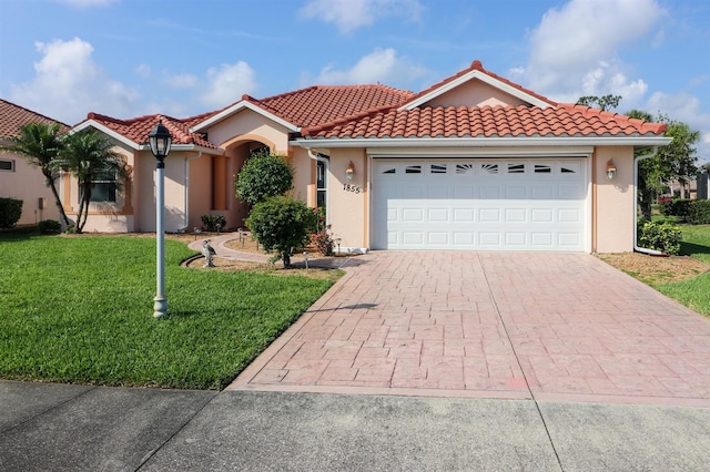 1855 Silver Palm Rd, North Port, FL 34288 - mediterranean / spanish-style home with decorative driveway, a front lawn, a garage, stucco siding, and a tiled roof