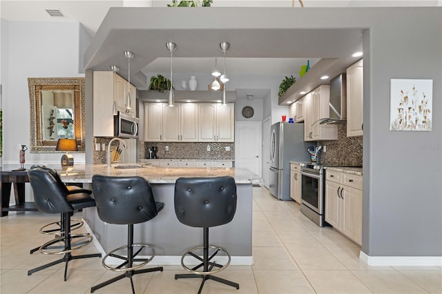 1422 Via Milanese, Punta Gorda, FL 33950 - kitchen featuring wall chimney range hood, appliances with stainless steel finishes, a peninsula, light stone countertops, and a breakfast bar