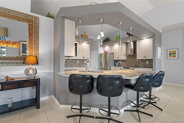 1422 Via Milanese, Punta Gorda, FL 33950 - kitchen featuring wall chimney exhaust hood, appliances with stainless steel finishes, decorative backsplash, light stone countertops, and a peninsula