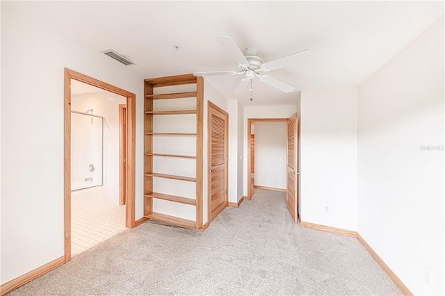 interior space with ensuite bathroom, a closet, light colored carpet, and ceiling fan