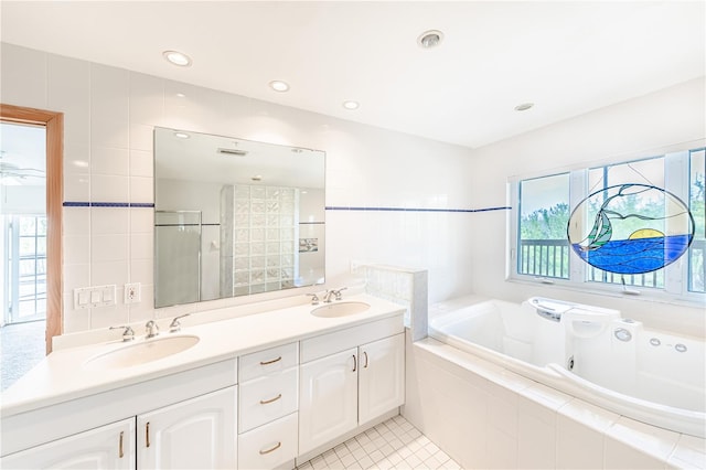 bathroom with tile patterned floors, tile walls, tiled bath, and dual bowl vanity