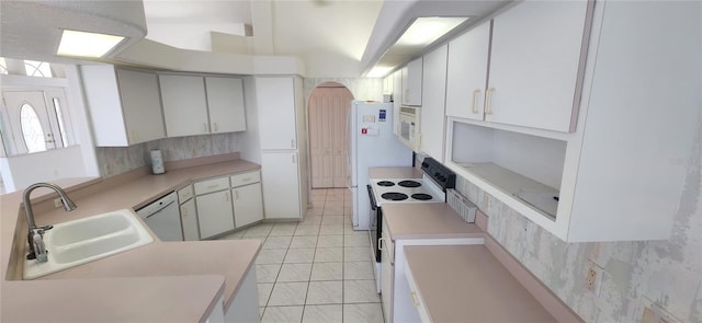 kitchen featuring sink, white appliances, light tile patterned floors, and white cabinets