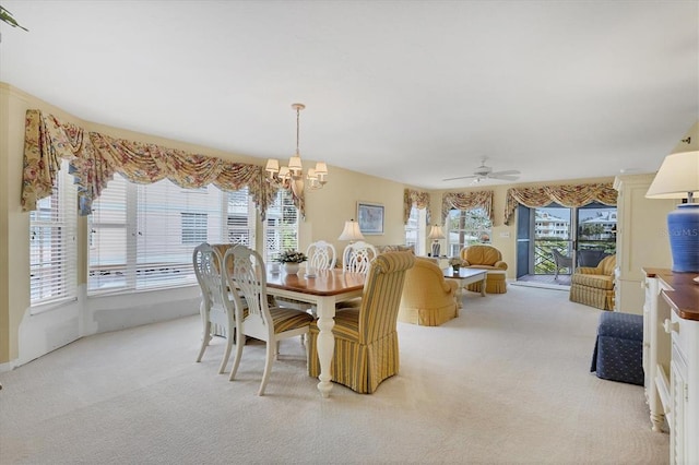 dining space with light carpet, plenty of natural light, and ceiling fan with notable chandelier