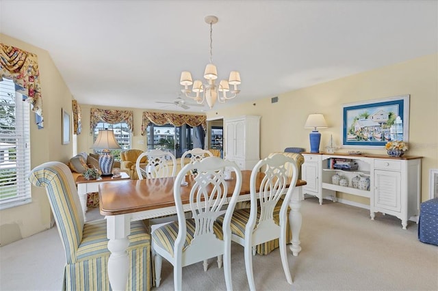 carpeted dining space with ceiling fan with notable chandelier and a wealth of natural light