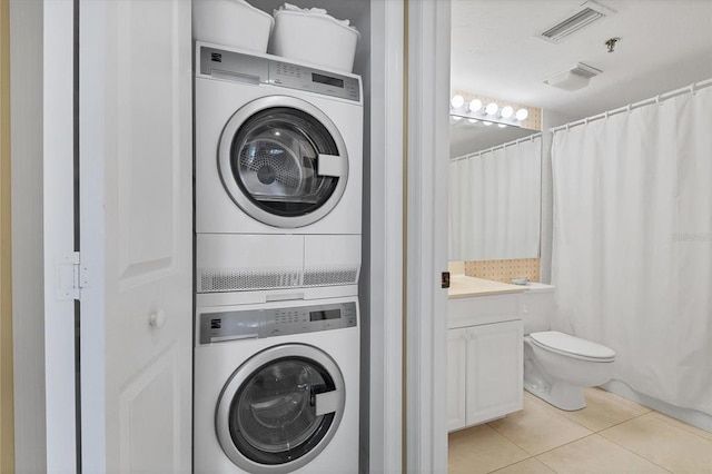 laundry area featuring light tile flooring and stacked washing maching and dryer