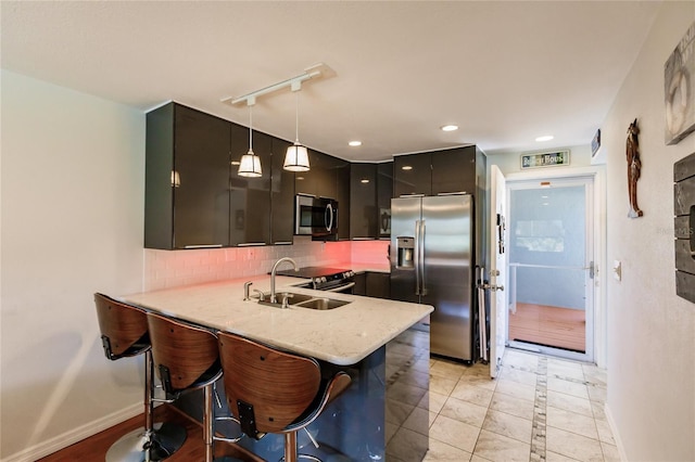 kitchen with backsplash, light tile floors, hanging light fixtures, sink, and appliances with stainless steel finishes