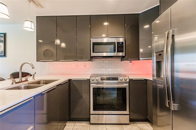 kitchen featuring tasteful backsplash, decorative light fixtures, light tile floors, sink, and appliances with stainless steel finishes