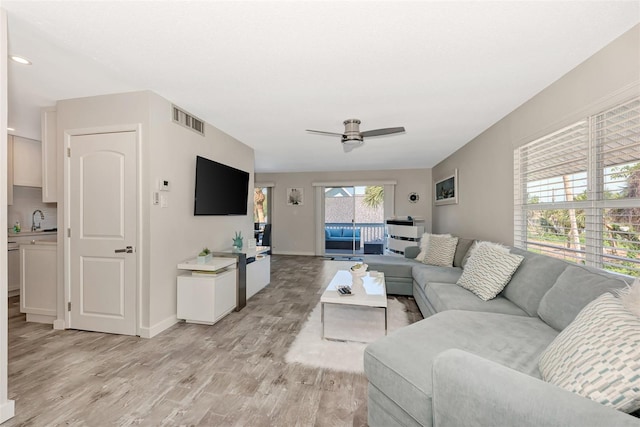 living room featuring sink, ceiling fan, and light wood-type flooring