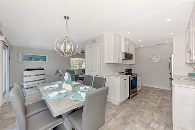 dining room featuring an inviting chandelier, sink, and light hardwood / wood-style flooring