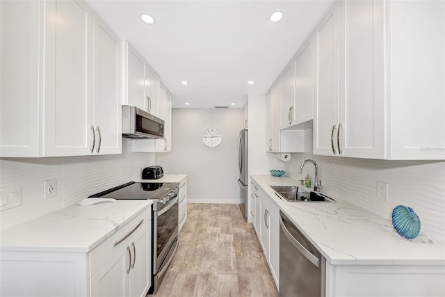 kitchen with white cabinetry, light hardwood / wood-style floors, sink, stainless steel appliances, and light stone counters