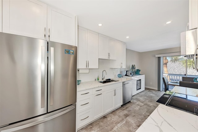 kitchen featuring white cabinetry, backsplash, sink, stainless steel appliances, and light stone counters