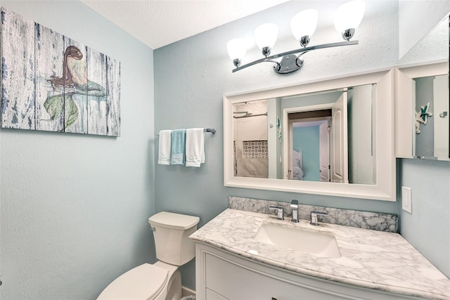 bathroom with toilet, a textured ceiling, and vanity with extensive cabinet space