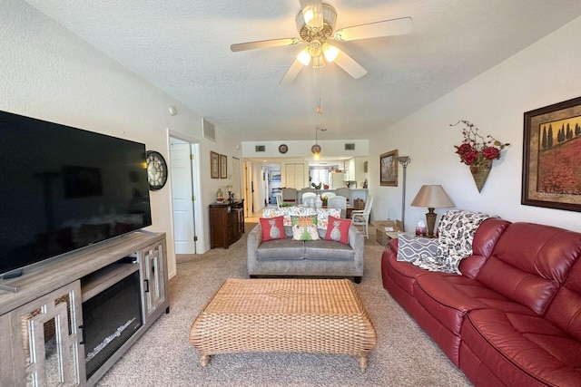 living room with light carpet, ceiling fan, and a textured ceiling