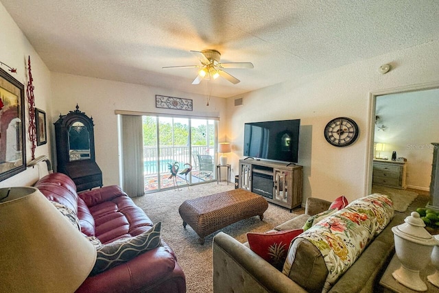 carpeted living room featuring ceiling fan, a textured ceiling, and a fireplace