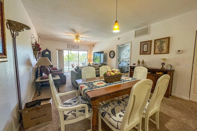 carpeted dining room with a textured ceiling and ceiling fan