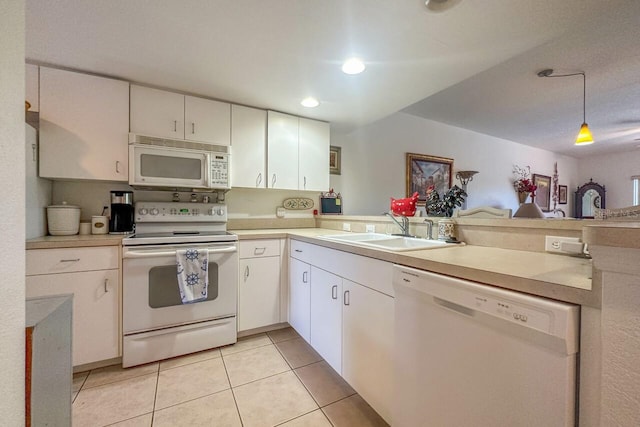 kitchen with light tile floors, kitchen peninsula, white appliances, white cabinets, and sink