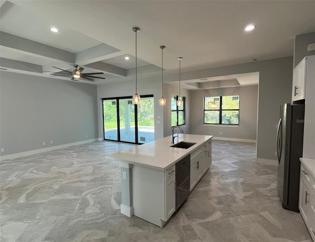 kitchen featuring ceiling fan, a center island with sink, white cabinetry, stainless steel fridge, and hanging light fixtures