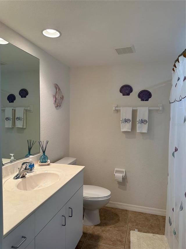 bathroom featuring toilet, vanity, and tile flooring