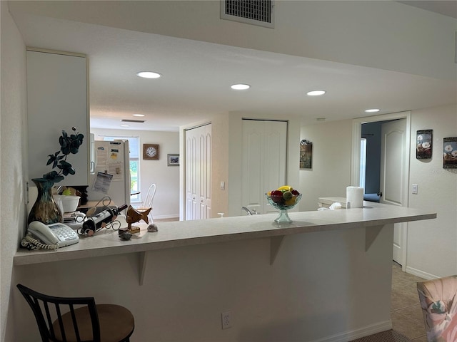 kitchen featuring light tile flooring, a kitchen breakfast bar, and white refrigerator