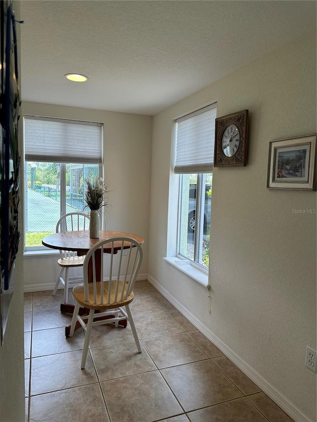 tiled dining area with a textured ceiling and a healthy amount of sunlight