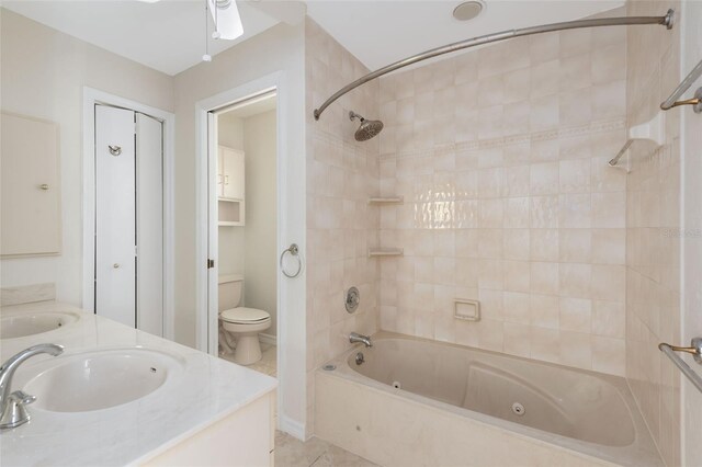 full bathroom with ceiling fan, toilet, tiled shower / bath, tile flooring, and dual vanity