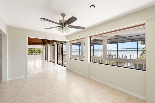 tiled empty room with ceiling fan and a water view