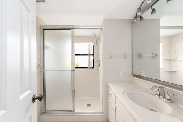 bathroom featuring a shower with door and vanity