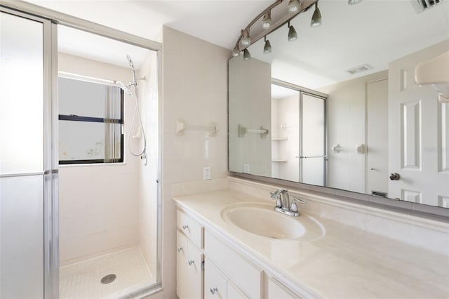 bathroom featuring a shower with door and vanity