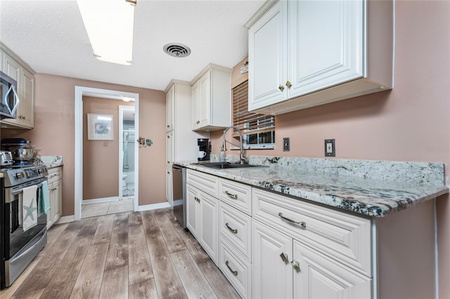 kitchen with white cabinets, light stone countertops, sink, and appliances with stainless steel finishes