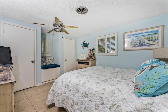 tiled bedroom with ceiling fan and a textured ceiling