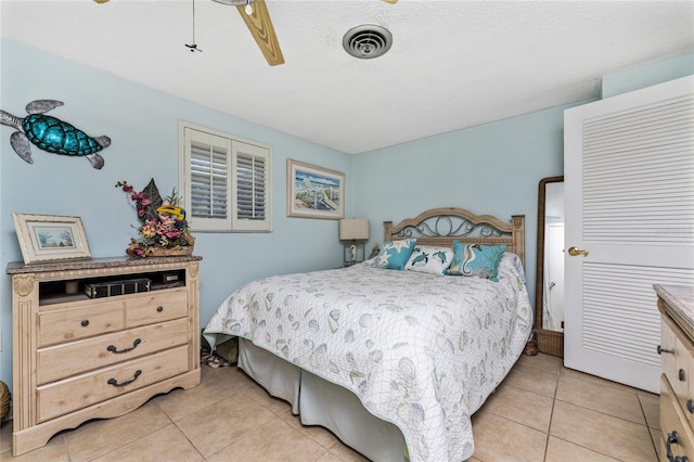 bedroom with ceiling fan, light tile patterned flooring, and a textured ceiling