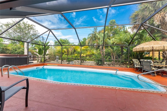 view of pool featuring a patio, glass enclosure, and a hot tub