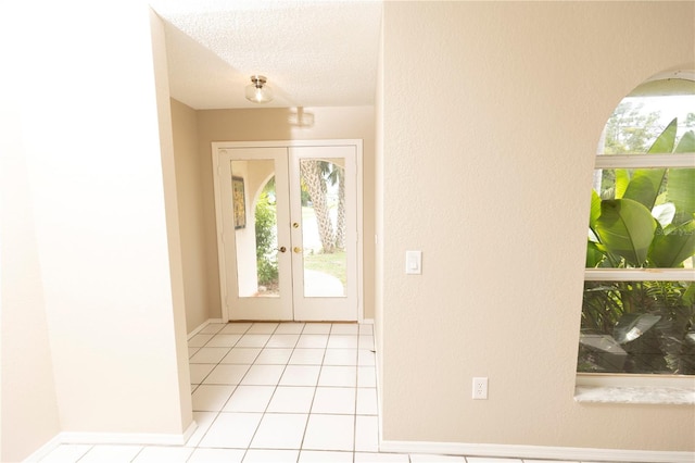 tiled foyer entrance featuring french doors, a textured ceiling, and a healthy amount of sunlight