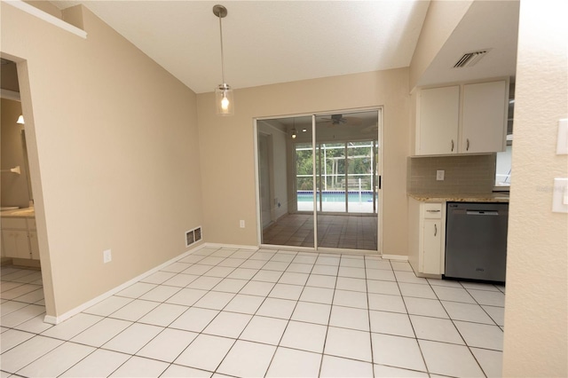 kitchen with decorative light fixtures, white cabinets, stainless steel dishwasher, light tile floors, and vaulted ceiling