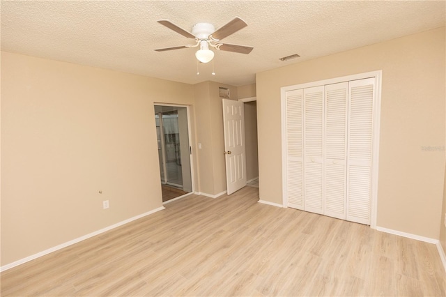 unfurnished bedroom featuring ceiling fan, a textured ceiling, light hardwood / wood-style floors, and a closet