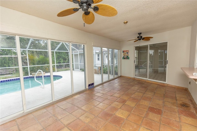 unfurnished sunroom featuring ceiling fan