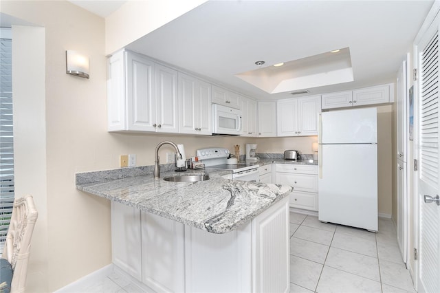 kitchen with white appliances, white cabinetry, a tray ceiling, and sink