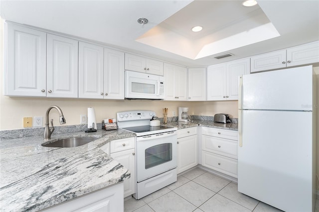 kitchen with light tile flooring, white appliances, sink, white cabinets, and a raised ceiling