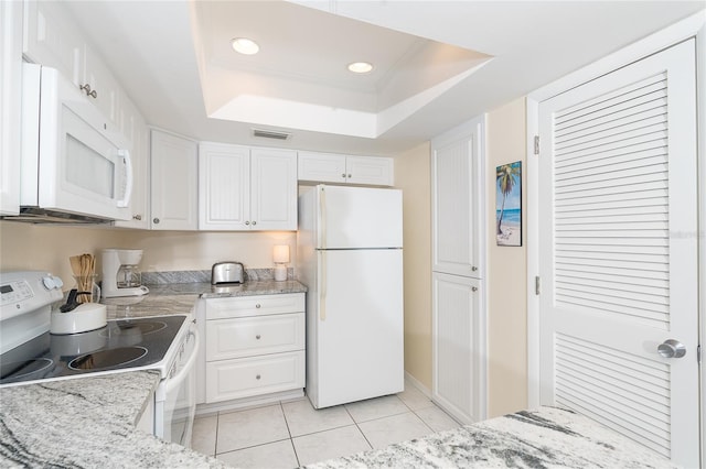 kitchen with white appliances, light tile floors, light stone counters, white cabinets, and a tray ceiling