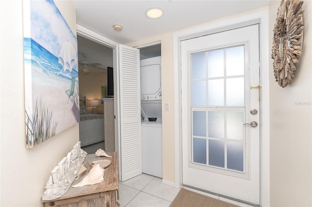 doorway featuring stacked washing maching and dryer, ceiling fan, and light tile floors