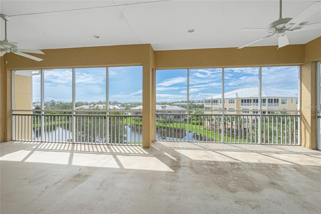 unfurnished sunroom with plenty of natural light, ceiling fan, and a water view